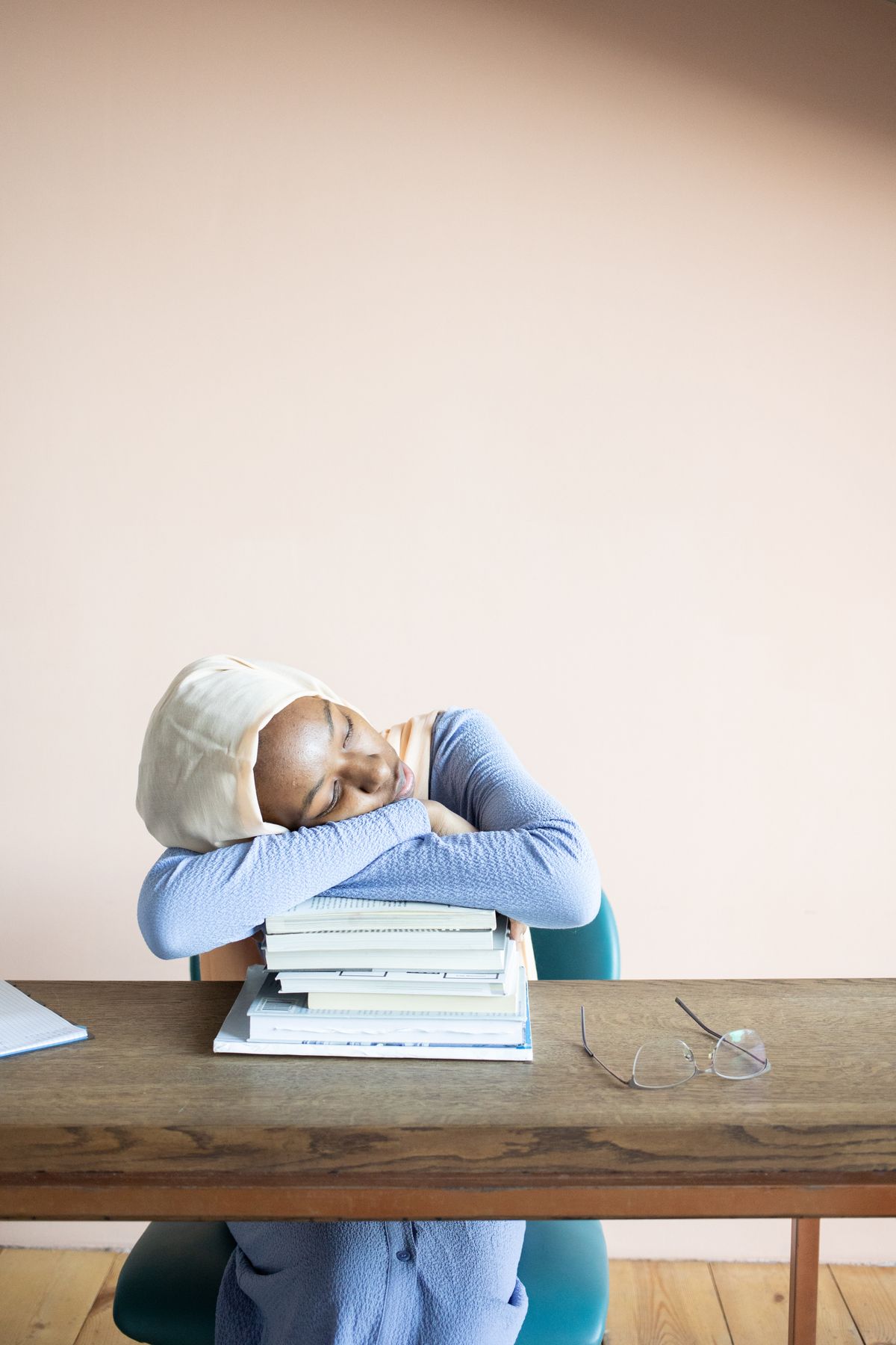 Eine müde Studentin schläft auf einem Bücherstapel