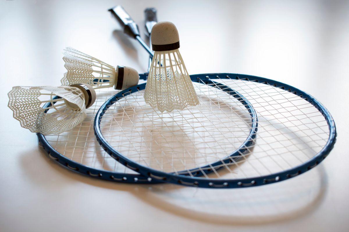 Badminton raketiyle tüy topa vuran bir oyuncu