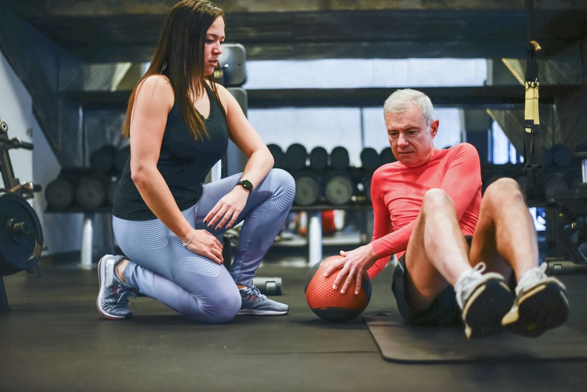 Un uomo anziano si allena con un personal trainer